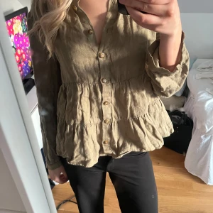 Grön blus Zara - Säljer en snygg grön blus med knappar framtill. Blusen har en avslappnad passform med volangdetaljer och långa ärmar. Perfekt för en stilren look. Strl M men passar mer som S! Från Zara🙌🏻