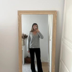 Grå v-ringad stickad tröja - Säljer en enkel och stilren grå stickad tröja med v-ringning. Tröjan har lång ärm och en avslappnad passform, perfekt att matcha med jeans eller kostymbyxor.