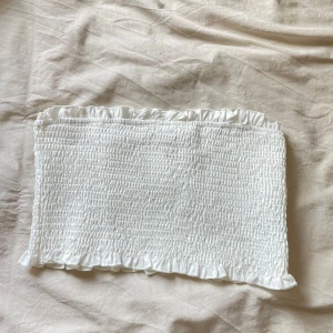 Vit tubtopp  -  söt vit tubtopp med smockad design och volangdetaljer upptill och nedtill. 