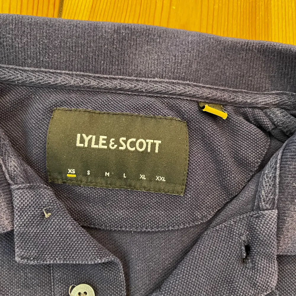 Säljer en stilren mörkblå pikétröja från Lyle & Scott inför våren eller sommaren. Tröjan är använd och kan anses lite urtvättad men inget att lägga märke till. (Inga fläckar). T-paidat.