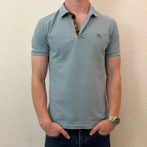 Ljusblå pikétröja från Burberry - Säljer nu min pikétröja från burberry då den blivit på gränsen till för liten samt att den inte kommer till användning något mer, perfekt för sommaren. Skriv för frågor o funderingar 100% äkta, kvitto finns.