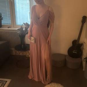 Säljer en elegant långklänning i dusty rosa med v-ringning, öppen rygg och slits framtill. Klänningen har offshoulder-ärmar och ett fint fall. Perfekt för bal eller fest! Materialet känns mjukt och följsamt. Så snygg och formar kroppen så så fint😁 från Asos som är helt slutsåld❤️ Lappar kvar på den så helt ny. Strl s men passar även M då den är stretchig