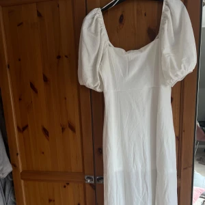 Vit långklänning med puffärm från Ginatricot - Säljer en vit långklänning från ginatricot med puffärmar och fyrkantig urringning. Klänningen har en elegant och enkel design med figurnära passform upptill och rak i längden. Jag är 180 cm lång och klänningen går över halva mina smalben, skulle därför passa både längre och kortare personer!! Perfekt till student eller andra sommartillfällen!!🌸💞