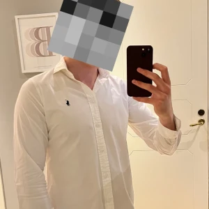 Vit skjorta från Polo Ralph Lauren - Klassisk vit skjorta från Polo Ralph Lauren med broderad marinblå logga på bröstet. Perfekt för dig som gillar en clean och snygg look. Storlek 10, vilket motsvarar ungefär storlek S. Jag är 180 cm lång och den sitter rätt så tajt på mig! Hör av dig vid frågor om storleken så svarar jag snabbt :)