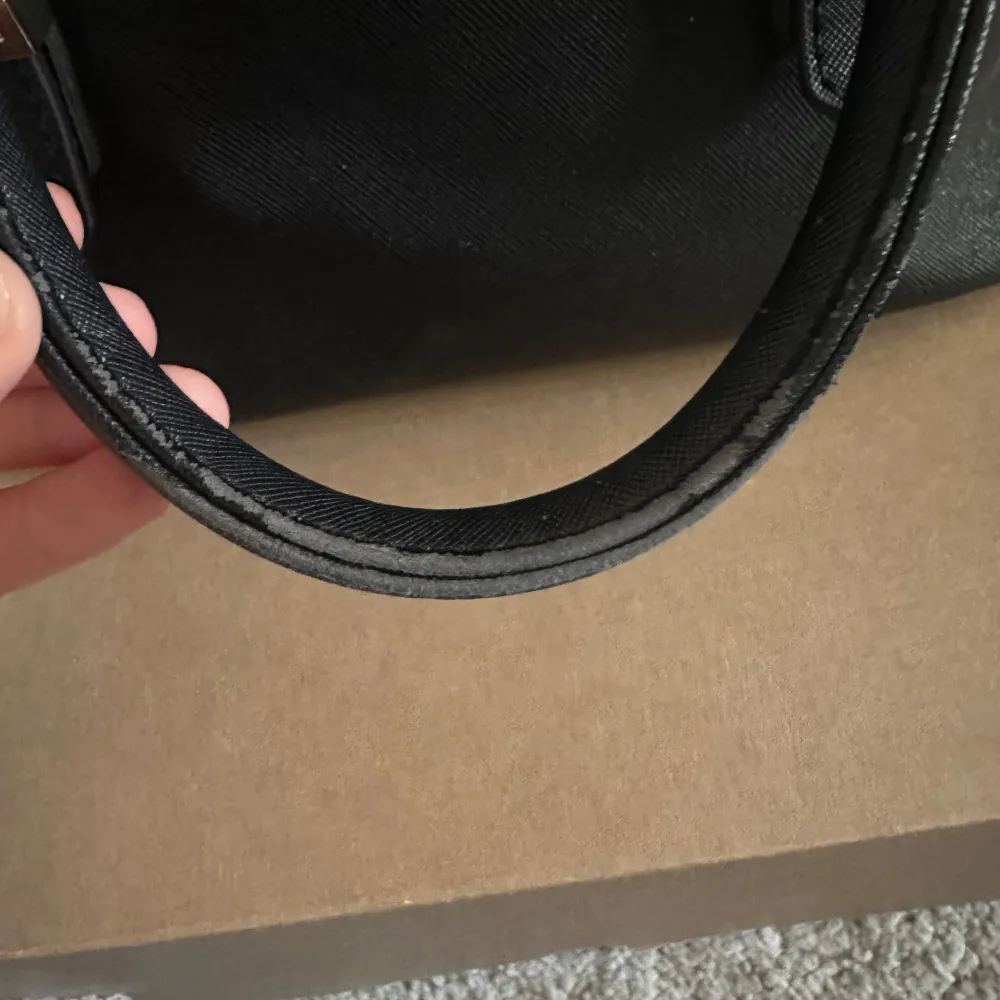 Snygg svart handväska från Guess med guldfärgade detaljer och dragkedja. Väskan har två handtag och är perfekt för att bära dina nödvändigheter med stil. Guess-loggan pryder framsidan och ger en lyxig touch.. Laukut & Käsilaukut.