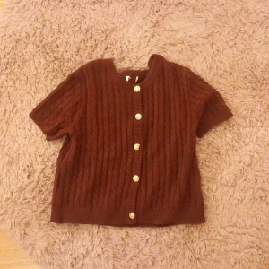 Vinröd kortärmad kofta med guldknappar - Säljer en kortärmad kabelstickad kofta i vinrött och den är jätte fint skick. Lappen är av klippt men tröjan är från hm och är i storlek M eller S men passar båda!💗💗