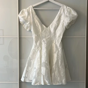 Studentklänning med puffärm - Superfin vit kortklänning med puffärmar, v-ringning och hyfsat djup rygg. Perfekt för studenten eller sommarens speciella tillfällen. Köpt från showpo för 1400kr. Är i storlek 36 men upfattas mindre i storlek. Helt oanvänd!