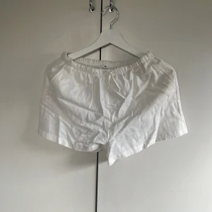 Vita linneshorts från H&M - Säljer ett par vita linneshorts från H&M i luftig linneblandning. De har resår i midjan med dragsko och sidofickor. Perfekta för varma dagar och enkel att matcha med olika toppar. Storlek 170 barn. Passar perfekt till en person med storlek S. Aldrig använda.