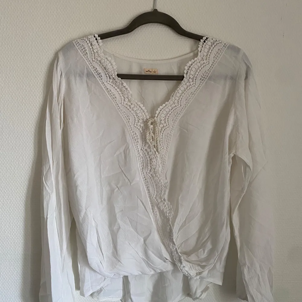 Denna vita blus från HOLLISTER är ett mångsidigt och stilrent plagg som passar perfekt för alla tillfällen. Den är tillverkad av ett lätt och luftigt material som känns bekvämt mot huden. Blusen har en klassisk design med en elegant krage och knytning framtill. Den har en avslappnad passform som smickrar alla kroppstyper. Den vita färgen gör den lätt att matcha med andra plagg i din garderob. . Puserot.