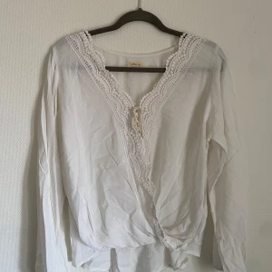 Vit blus från HOLLISTER - Denna vita blus från HOLLISTER är ett mångsidigt och stilrent plagg som passar perfekt för alla tillfällen. Den är tillverkad av ett lätt och luftigt material som känns bekvämt mot huden. Blusen har en klassisk design med en elegant krage och knytning framtill. Den har en avslappnad passform som smickrar alla kroppstyper. Den vita färgen gör den lätt att matcha med andra plagg i din garderob. 