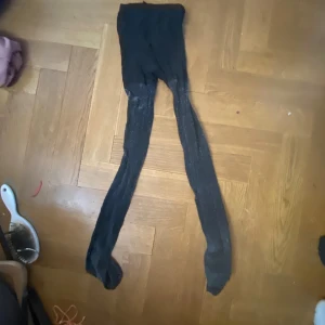 Svarta och glittrande strumpbyxor - Svarta, tunna strumpbyxor med klassisk passform. Perfekta att bära under kjol eller klänning för en stilren look. Materialet är lätt och följsamt.
