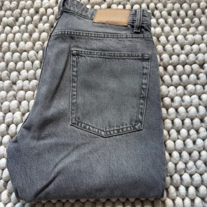 Grå jeans från ZARA - Säljer ett par grå jeans från ZARA med klassisk femficksdesign och raka ben. Jeansen har normal passform och är tillverkade i ett mjukt denimtyg. Perfekta för en stilren och avslappnad look.
