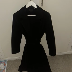 Svart kappa från Vero Moda med bälte - Stilren svart kappa från Vero Moda med klassisk krage och bälte i midjan. Använd en gång 💕 jätte fin på och formar verkligen kroppen