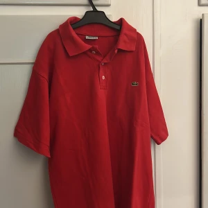 Röd pikétröja från Lacoste - Klassisk röd pikétröja från Lacoste, perfekt till sommaren snygg också.