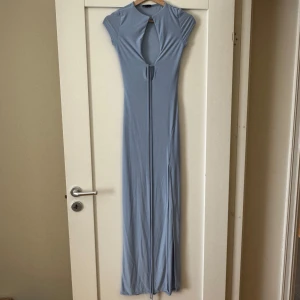 Ljusblå långklänning med knyt - Säljer en ljusblå långklänning från ASOS med korta ärmar och snygg v-ringning framtill. Klänningen har ett knyt under bysten och är figurnära upptill. Perfekt för sommarens tillfällen!