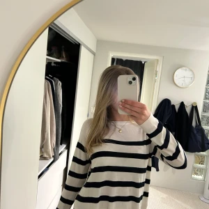 Vit och marinblå randig croppad tröja - Säljer en vit croppad tröja med marinblå breda ränder. Tröjan har långa ärmar och en avslappnad passform. Perfekt till jeans eller kjol för en enkel och stilren look.