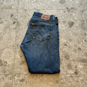 Levi's 501 blå jeans - Klassiska blå Levi's 501 jeans med raka ben. Storleken är W34, L32. Väldigt snygga jeans enligt mig och är i bra skick. Nypriset ligger på cirka 1400 så ett väldigt bra pris.