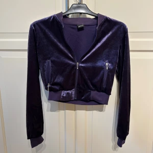 Lila sammetsjacka från Gina Tricot - Säljer en lila croppad sammetsjacka från Gina Tricot med dragkedja framtill och två fickor med dragkedja. Jackan har långa ärmar och bred mudd vid midjan och ärmsluten. I strl xs