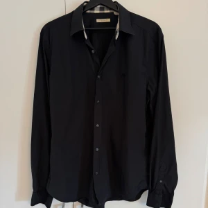 Svart Burberry Brit skjorta  - Burberry Brit skjorta i storlek:XL, 9/10 i väldigt bra skick som ny nästan använt fåtal gånger. Äkthetscertifikat medföljer! Pris:1100kr