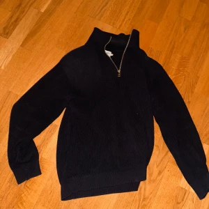 Svart stickad tröja med dragkedja från EAST WEST - Mysig svart stickad tröja från EAST WEST med halv dragkedja vid halsen. Tröjan har hög krage och långa ärmar, perfekt för kyligare dagar. Enkel och stilren design som passar till mycket. Köpte för 1000kr. Pris går att diskutera.