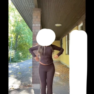 Sett/ Brun zip kofta och byxor från Gina Tricot  - Mörkbrun kofta med dragkedja från Gina Tricot. Jackan har lång ärm, figurnära passform och är tillverkad i mjukt bomullsmaterial med lite stretch. Perfekt för lager-på-lager och enkel att matcha med olika outfits. Kofta: s byxor: xs