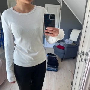 Vit ribbad långärmad tröja - Enkel och stilren vit långärmad tröja med ribbad struktur. Perfekt basplagg som passar till allt, rund halsringning och mjukt material. Ett pyttelitet hål på vänstra axeln annars inga defekter😙