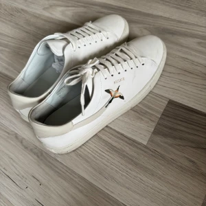  Clean 90 Axel Arigato  - Säljer ett par vita clean 90 Axel Arigato med en snygg broderad fågel på sidan. Skorna är i storlek 42 och är använda ett par gånger. För dig som vill diskutera pris och köpa de inför det kommande sommaren skriv! Du som gillar stilrena och trendiga skor men även från Axel Arigato. 