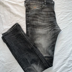 Hugo Boss jeans - Säljer nu ett par extremt feta Hugo Boss jeans i slim fit modell🥳. Dom är köpta i London för cirka 2000kr som nypris och säljs nu för endast 299kr💪Dom är svarta/gråa i färgen och har extremt snygga ”wash” detaljer. Det finns vissa tecken på användning som slitage på vissa ställen, lagning vid skrevet, sönder nött färg på loggorna. Vid frågor hör gärna av er🤝