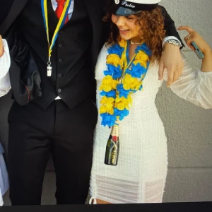 Studentklänning - Säljer en vit kortklänning med långärmade, transparenta ärmar. Den är V-ringad. Klänningen har rynkade detaljer framtill 2 st och baktill som ger en snygg passform. Perfekt till student eller sommarens fester! Skönt mesh material och väldigt luftig och skön. Överkjolen är längre än underkjolen vilket är så fint och den har knytning längts ner. Använd 1 gång🌸 köpt för 900kr