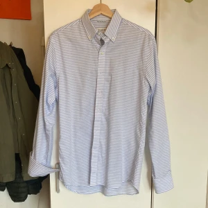 Blåvit randig skjorta från John Henric - Skjorta från John Henric i blåvitt randigt mönster. Mycket fint skick, säljer så den är något för stor på mig