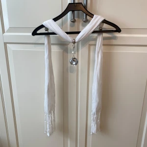 Vitt tyg Bälte med diamant dekoration - Säljer ett vitt tyg bälte med fransar i ändarna och en diamant dekoration i mitten. 