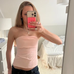 Ljusrosa tubtopp - Säljer en ljusrosa tubtopp!🥰 Toppen är axelbandslös och har en enkel, stilren design som passar perfekt till jeans eller kjol. Perfekt för varma dagar och fester