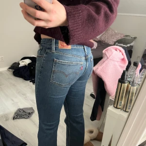 Blå Superlow Bootcut jeans från Levi's - Säljer ett par klassiska blå Levi's Superlow Bootcut jeans i storlek 27. Jeansen har låg midja och bootcut-ben, med snygga detaljer och den ikoniska Levi's-lappen bak. 