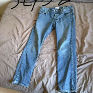 Blå jeans från Jack & Jones - Säljer ett par klassiska blå jeans från Jack & Jones med raka ben och knappgylf. Jeansen har fem fickor och är i en tidlös modell som passar till det mesta. Perfekta för dig som gillar enkel och stilren denim.