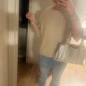 Beige stickad tröja med vida ärmar - Säljer en beige stickad tröja med avslappnad passform och vida trekvartsärmar. Tröjan har rund halsringning och är superenkel att styla till jeans eller kjol. Perfekt för dig som gillar en chill och stilren look. Tröjan är ganska nopprig