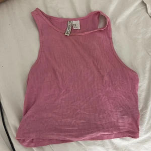 Rosa ribbad linnetopp från H&M Divided - Säljer en rosa ribbad linnetopp från H&M Divided i storlek XS. Toppen är ärmlös med rund halsringning och croppad passform. Perfekt för varma dagar och enkel att matcha med jeans eller kjol.