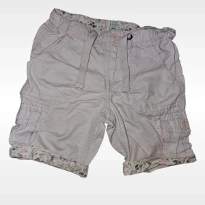 Ljusrosa shorts med blommigt foder L.O.G.G - Söta ljusrosa shorts från H&M med blommigt foder i midjan och vid bensluten. Shortsen har snörning i midjan, flera fickor och coola cargodetaljer. Perfekta för varma dagar och ger en chill vibe med sin loose passform och fina detaljer. Färgen är mest rättvis på bilden med justerbar midja.
