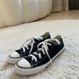 Svarta Converse All Star sneakers - Klassiska svarta Converse All Star sneakers med vit tå och sula, vita snören och kontrasterande sömmar. Skorna är aldrig använda och är i storlek 35 men passar definitivt en storlek 36 eftersom jag som 37 kan få på mig dom. Lite smuts här och var syns på nära håll pågrund av att de stått i hallen. ⚠️!Kontakta mig innan du klickar på köp! 