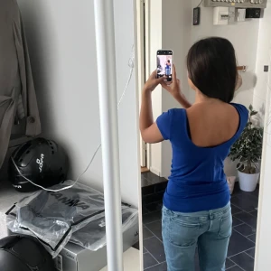 Blå topp med öppen rygg från H&M - Säljer en blå topp från H&M med tight passform och korta ärmar. Toppen har en djup, öppen rygg som ger en snygg och modern look. Tillverkad i mjuk bomull som känns skön mot huden. Perfekt för dig som gillar stilrena och enkla plagg med en twist.