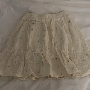 Vit broderad kjol Sofie Schnoor - Supersöt vit kjol från Sofie Schnoor med broderade blommor och volangkant. Kjolen har resår i midjan och är gjord i mjuk bomull, perfekt för sommarens alla äventyr. Lätt och luftig med fina detaljer, passar mig som är 166 cm