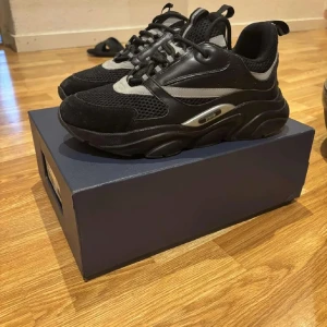 Svarta B22 sneakers storlek 41 - Chunky svarta B22 sneakers med grå och silverdetaljer. Ovandel i mesh och skinn med coola paneler och snörning. Tjock sula för extra attityd och komfort. Perfekta för dig som vill sticka ut med lyxig streetstyle. Perfekta skor till skolstart❤️