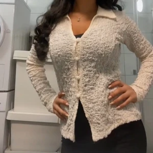 Beige crinkle kofta med knappar - Supersöt beige kofta från Gina Tricot med crinkle-effekt och stora tygklädda knappar. Långärmad och med klassisk krage, perfekt för lager-på-lager. Materialet känns lätt och stretchigt, vilket gör den både bekväm och snygg till jeans eller kjol.