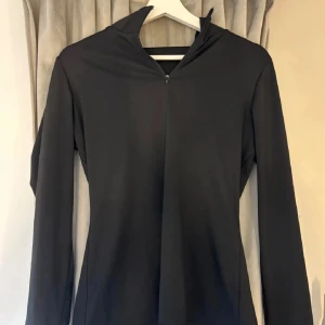 Svart långärmad half zip tröja - Svart långärmad tröja med half zip och hög krage. Enkel och stilren design som passar perfekt till träning eller chill. Materialet känns mjukt och stretchigt, vilket gör den bekväm att bära hela dagen.