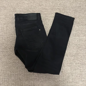 Replay Grover svarta jeans - Svarta Replay Grover jeans med klassisk femficksdesign och raka ben. Jeansen har snygga detaljer vid fickorna och en diskret logga på bakfickan. Tillverkade i stretchig bomullsblandning för skön passform och stilren look.