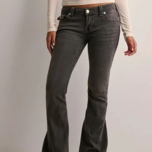 lågmidjade True Religion jeans - Lågmidjade true religion jeans i modellen joey- low rise flare. Säljer då dem är lite för stora och därför inte kommit till användning, sitter som S. Färgen är en urtvättad svart