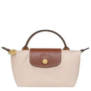 Longchamp väska - Snygg beige handväska från Longchamp med brunt skinnlock och guldfärgade detaljer. Klassisk design med kort handtag och tryckknapp framtill. Perfekt storlek för det viktigaste och lätt att matcha till olika outfits.
