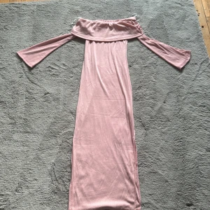Ljusrosa offshoulder långklänning - Supersöt rosa långklänning med offshoulder och långa ärma som går ut. Klänningen har en rak passform och är gjord i stretchig tyg. Perfekt för fina tillfällen. Använd en gång!