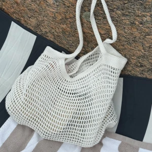 Virkad strandväska  - En luftig och rymlig strandväska virkad för hand. Den är lätt att rulla ihop i resväskan men tillräckligt rymlig för både handduk, bok, solkräm och snacks. Perfekt för stranddagar, marknader eller som en luftig vardagsväska. 