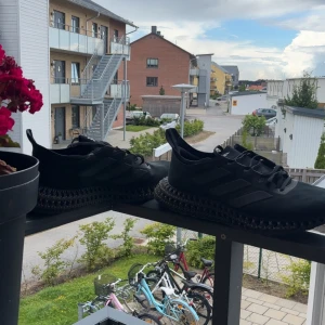 Svarta 4d adidas skor  - Säljer ett par svarta Adidas sneakers med futuristisk 3D-printad sula och klassiska tre ränder på sidan. Ovandelen är i mesh och syntet, med snörning och rund tå. Sulan är märkt Continental för extra grepp. Perfekta för dig som gillar techiga vibes.