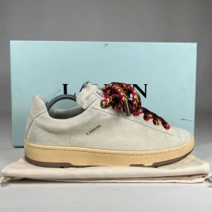 Lanvin Curbs  - Snygga sneakers från Lanvin i ljusbeige mocka med chunky, färgglada snören i rött, svart, gult och vitt. Skorna har en beige sula med bruna detaljer och diskret Lanvin-logga på sidan. Perfekta för dig som vill sticka ut med en stilren men unik look. Riktigt snygga Lanvin curbs ny pris 950€ som är 10 815kr skiv vid intresse eller funderingar 😊